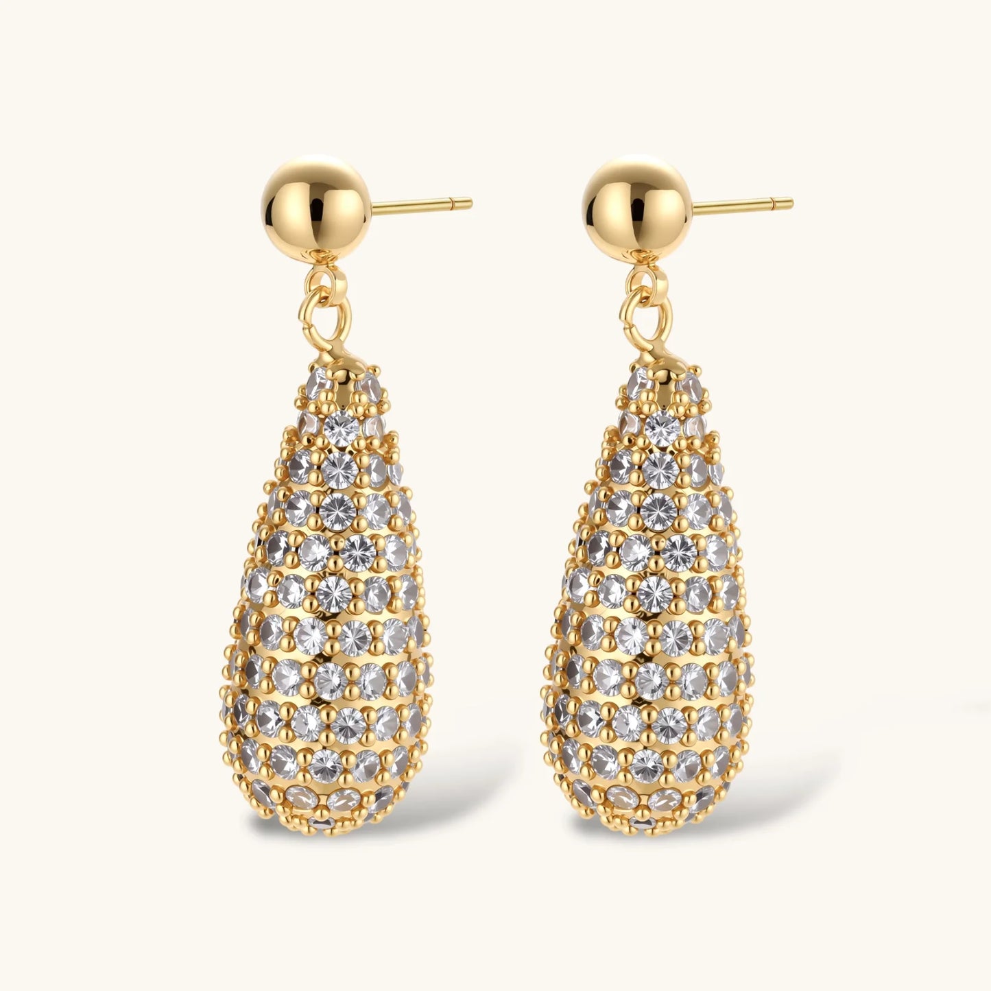 Gold-plated teardrop necklace and earrings covered in AAA cubic zirconia crystals on cream background.