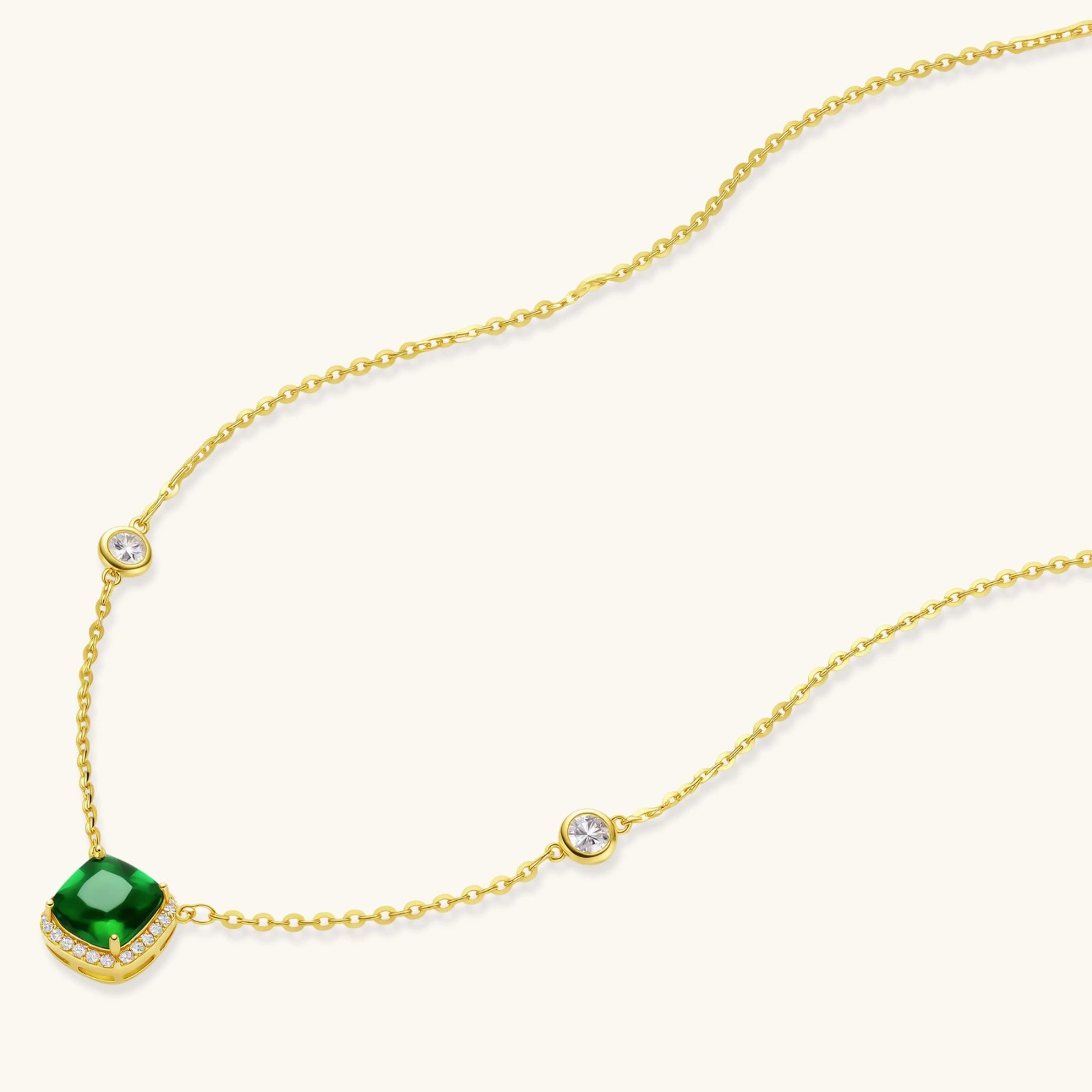 Delicate gold chain necklace featuring square emerald pendant with crystal halo and station accents