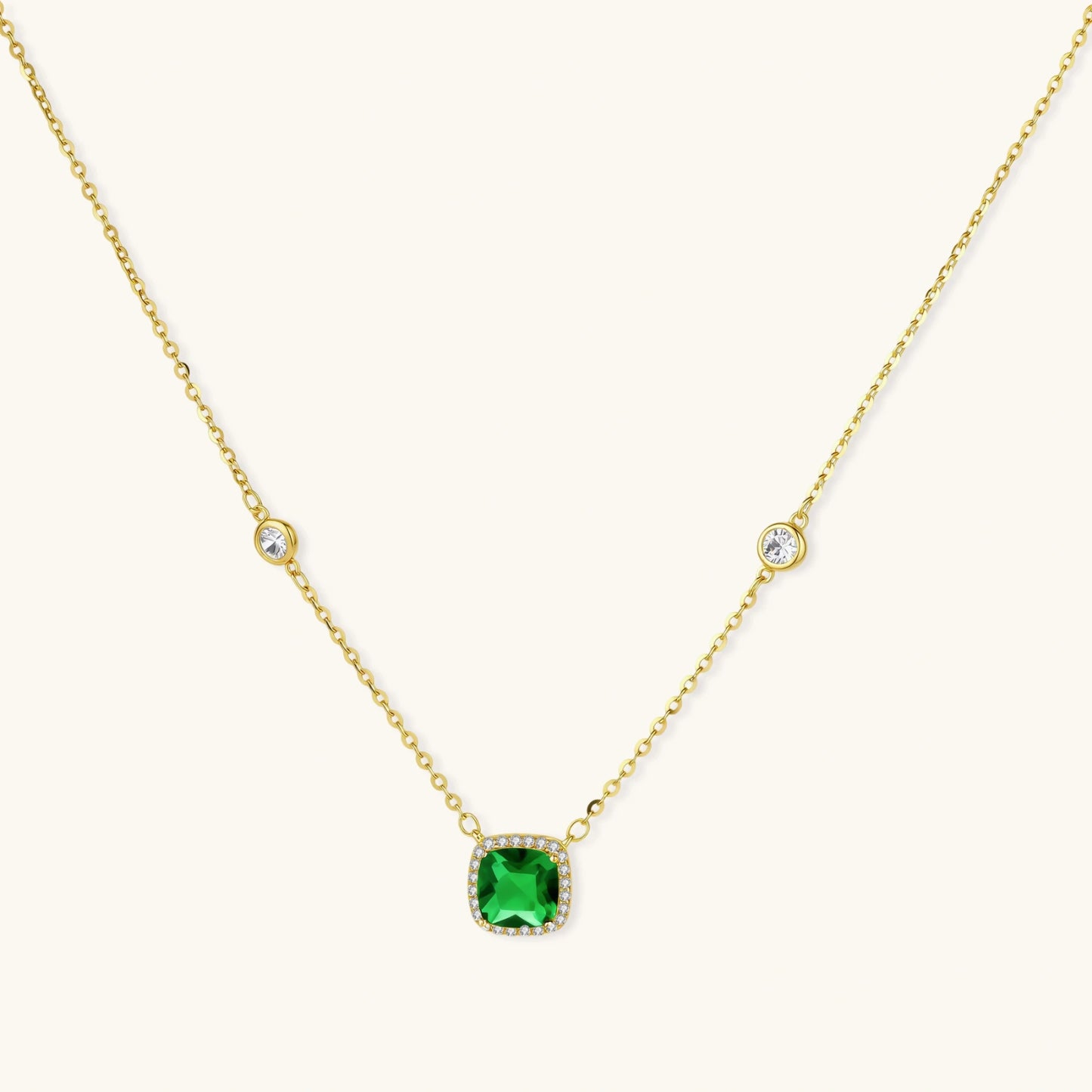 Delicate gold chain necklace featuring square emerald pendant with crystal halo and station accents