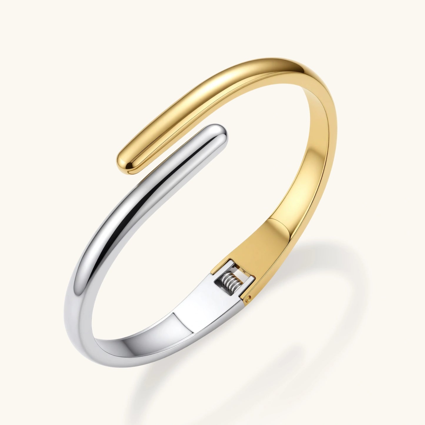 Polished two-tone bypass cuff bracelet in 18K gold plated and silver stainless steel with overlapping tapered ends.